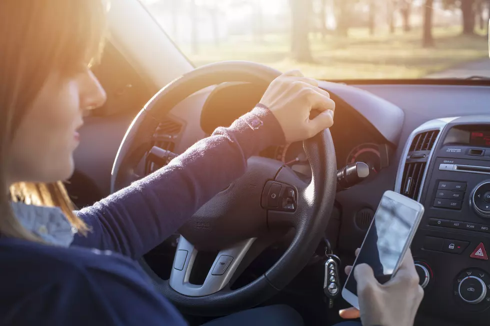 Young woman looking at her smartphone while driving a car. Distracted driver